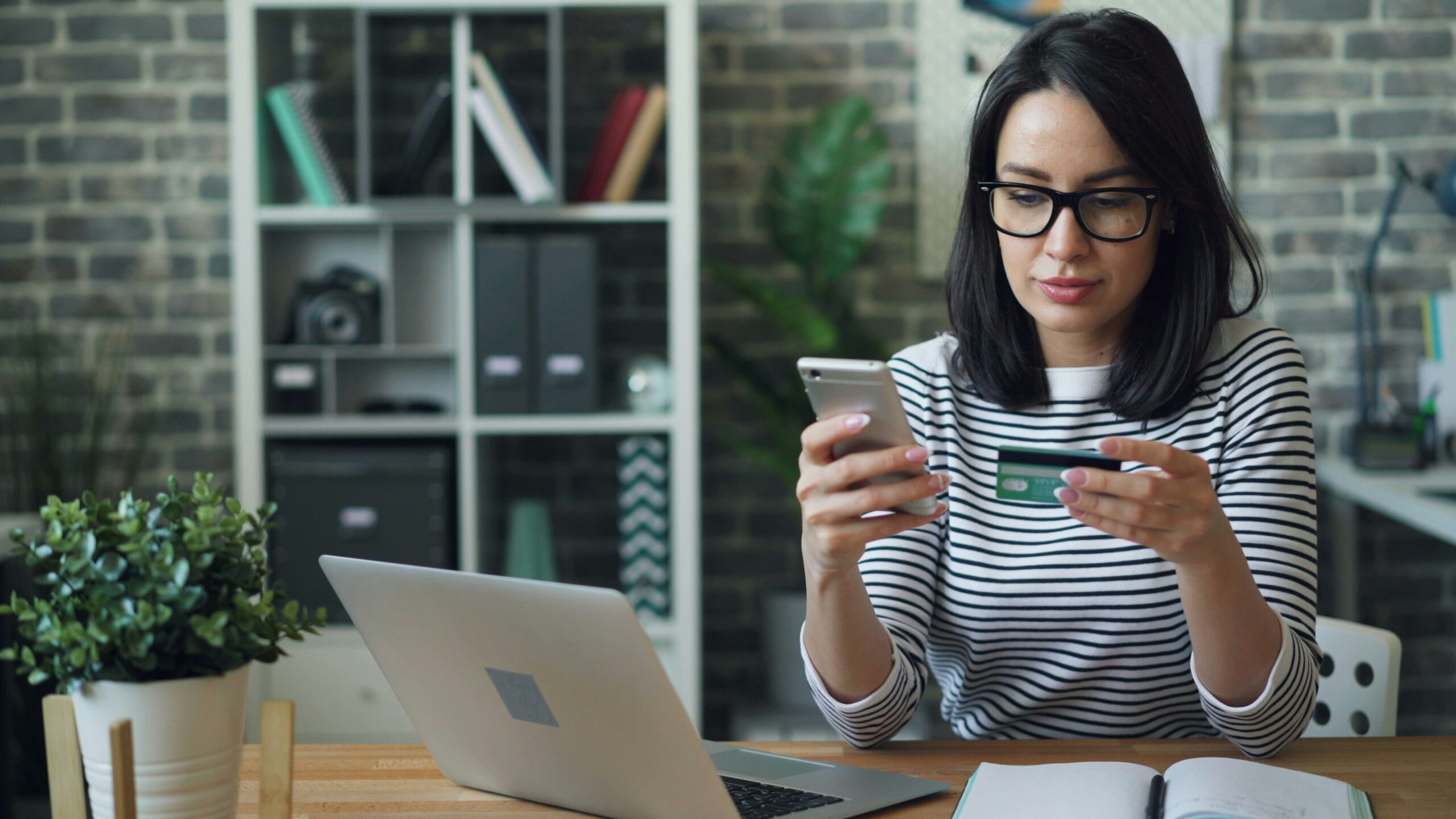 mujer revisando tarjeta de crédito en celular aprendiendo cómo salir de deudas paso a paso